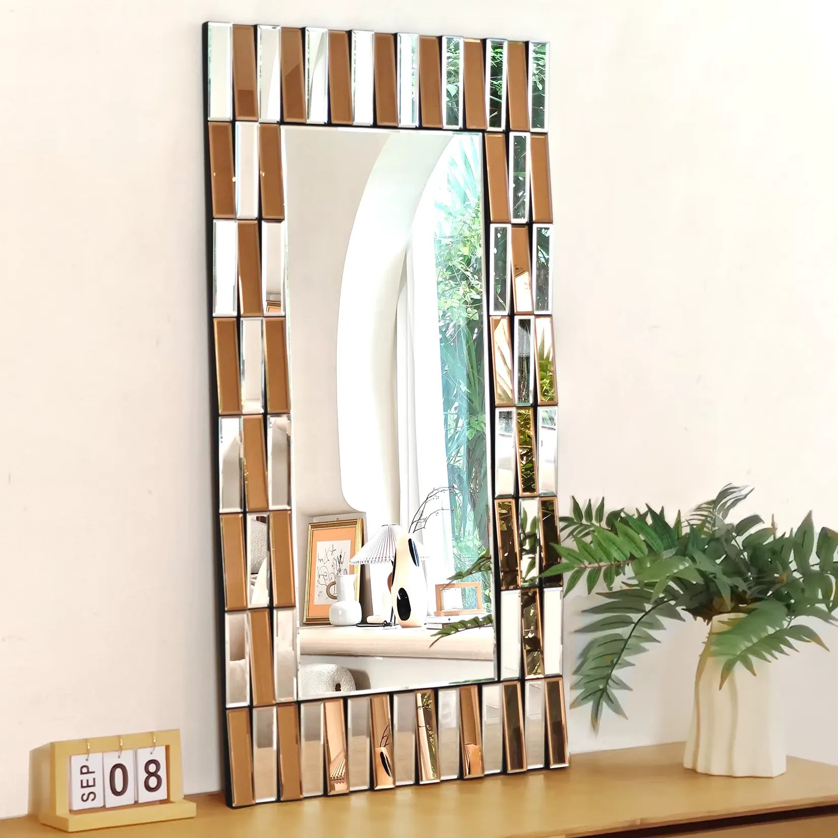 Miroir doré design accroché sur un mur en bois dans un décor naturel et chaleureux.