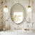 Miroir doré ovale dans un décor de salle de bain haut de gamme, avec détails dorés et fleurs.