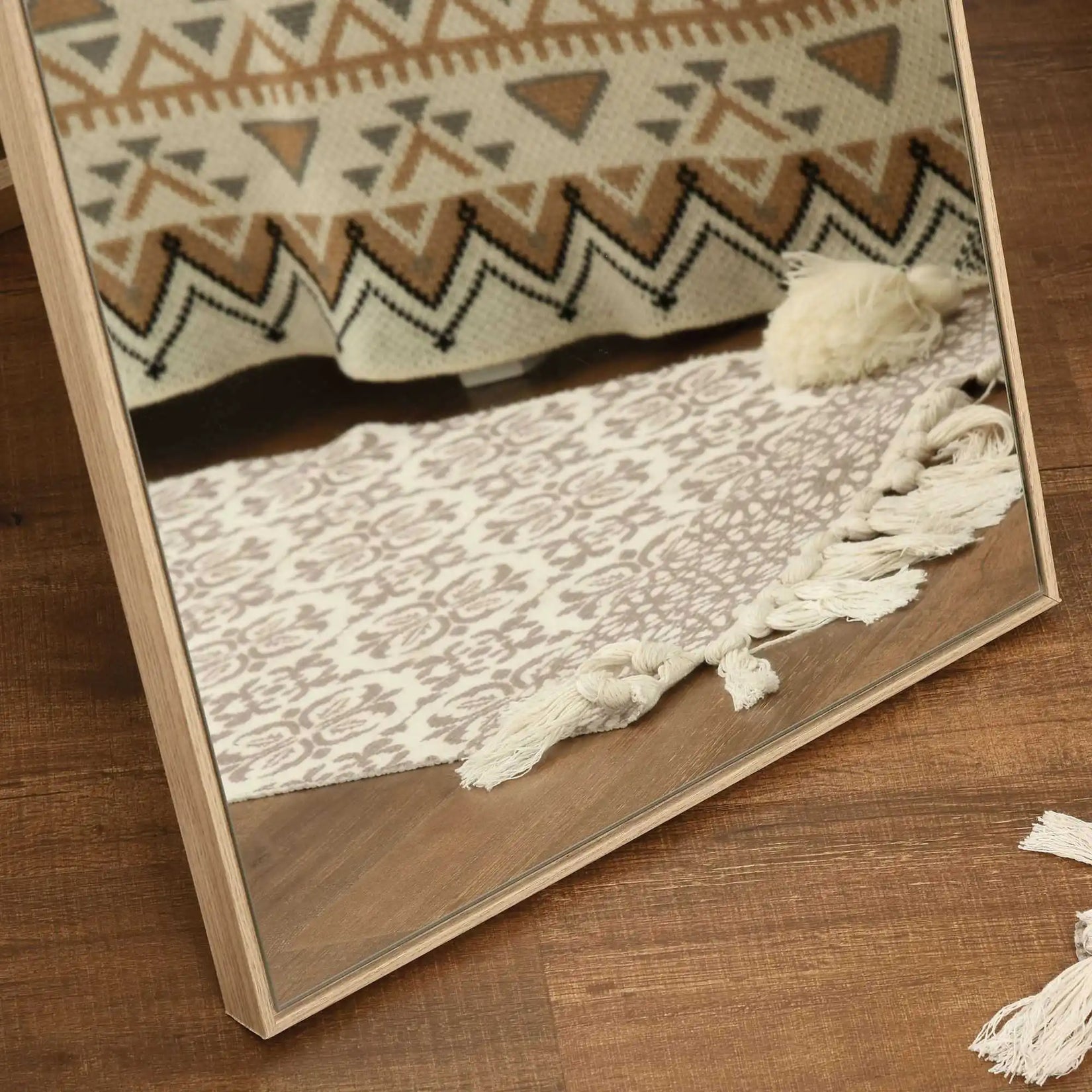 Vue rapprochée du cadre bois texturé du miroir en bois sur pied, posé sur un sol chaleureux en bois foncé.