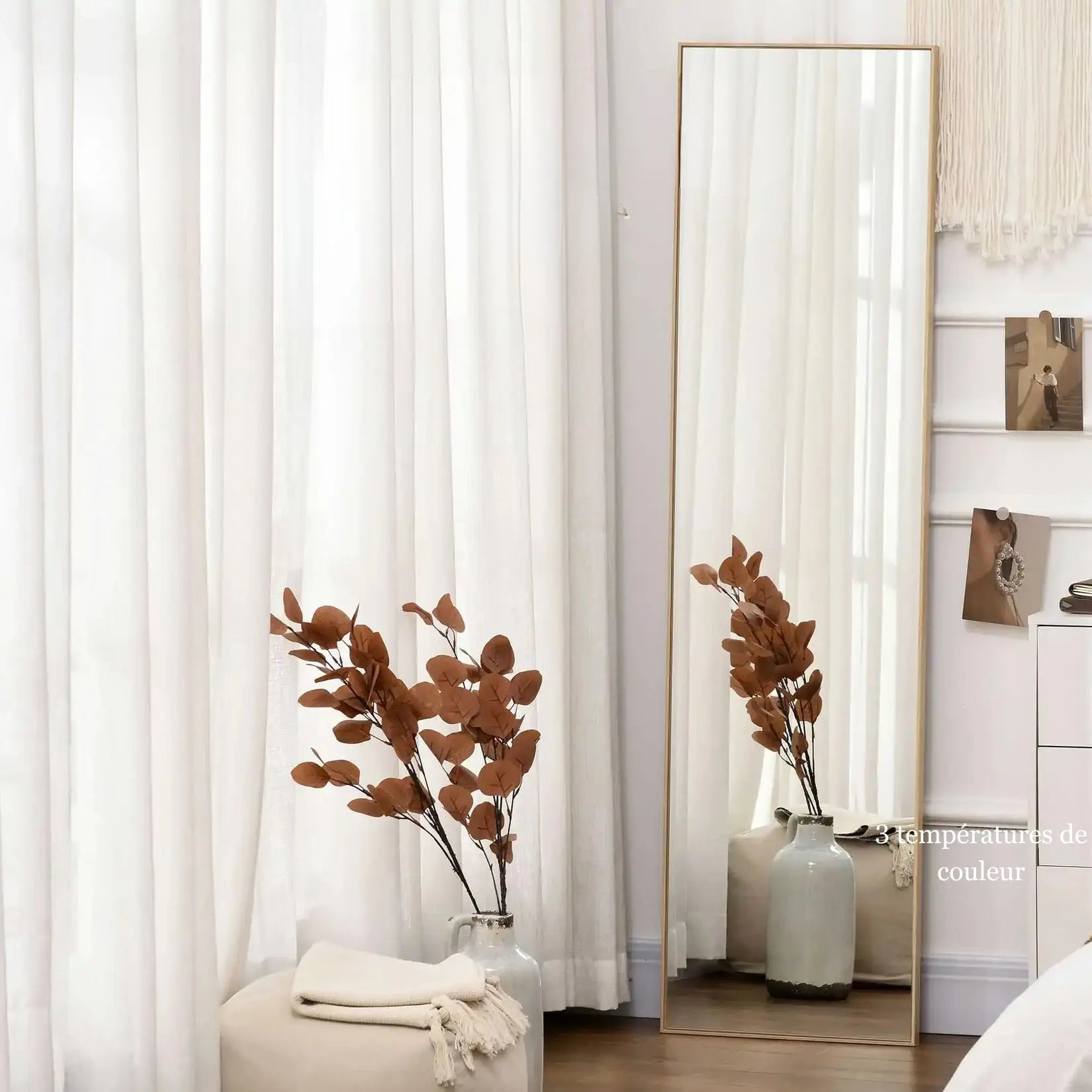 Miroir en bois sur pied installé dans une chambre lumineuse à la décoration naturelle et douce.