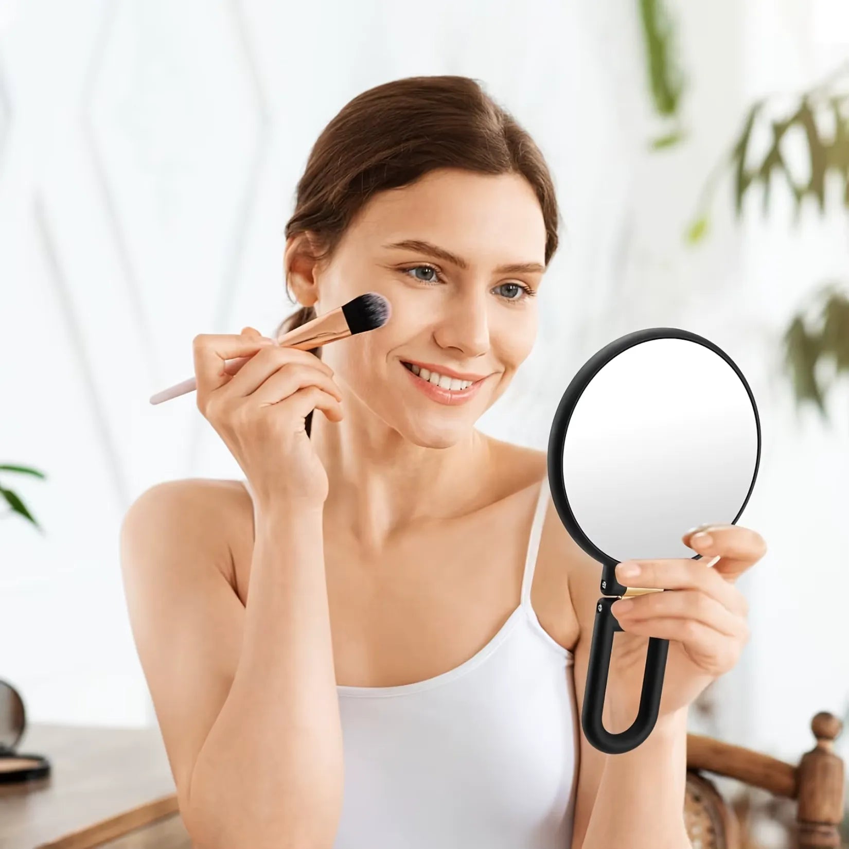 Femme appliquant du blush devant le miroir grossissant x50 tenu en main.