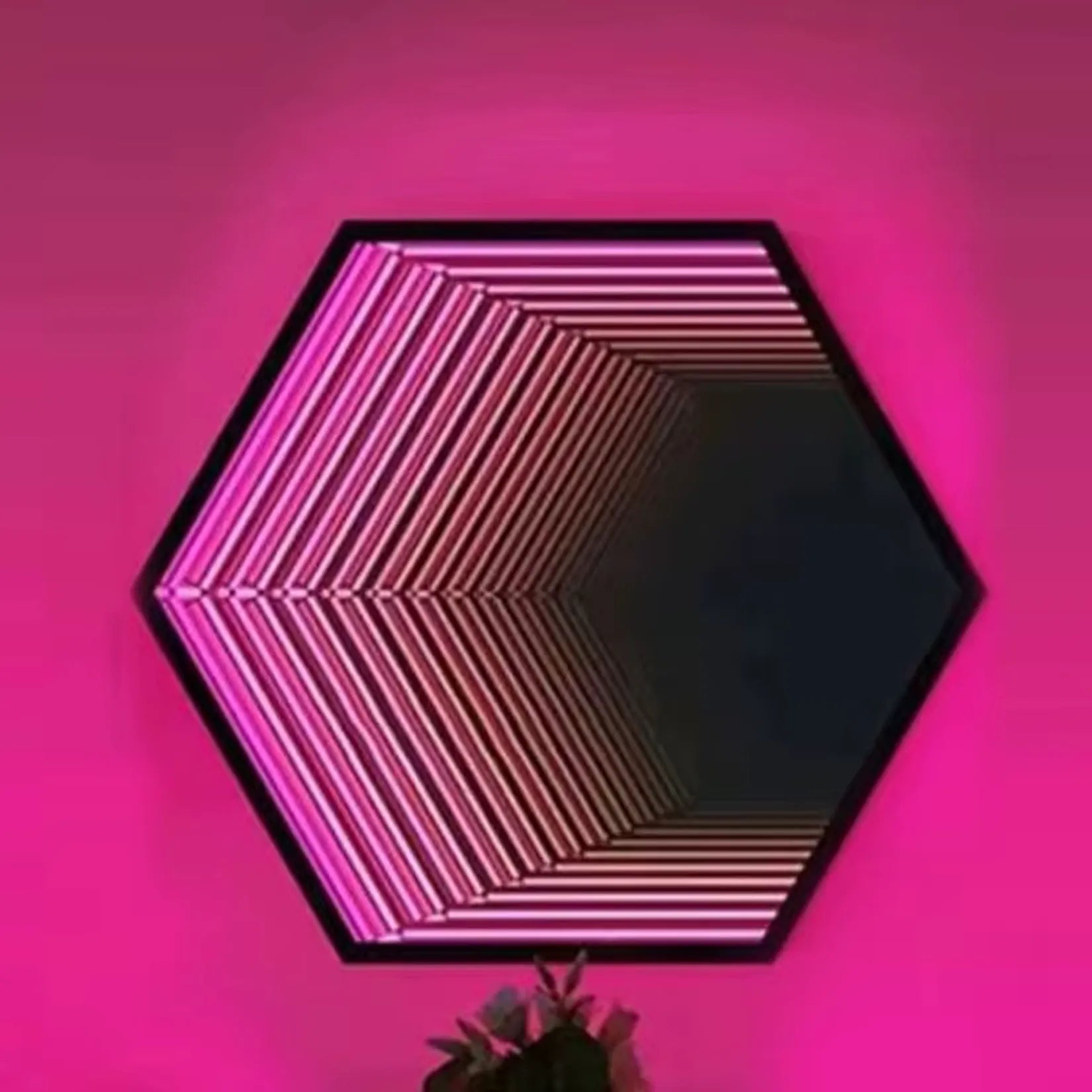 Miroir infini hexagonal en décoration murale – ambiance LED rose magenta.