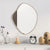 Miroir irrégulier doré au-dessus d’une console décorée d’objets et d’une bougie.