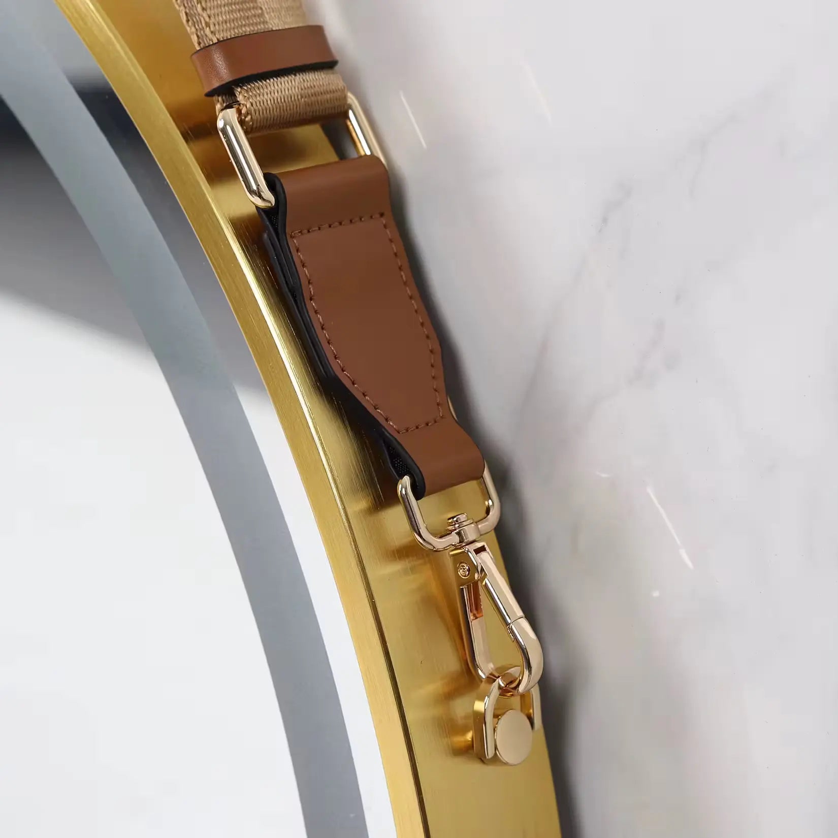 Détail du miroir LED rond doré – attache métallique et lanière de suspension.