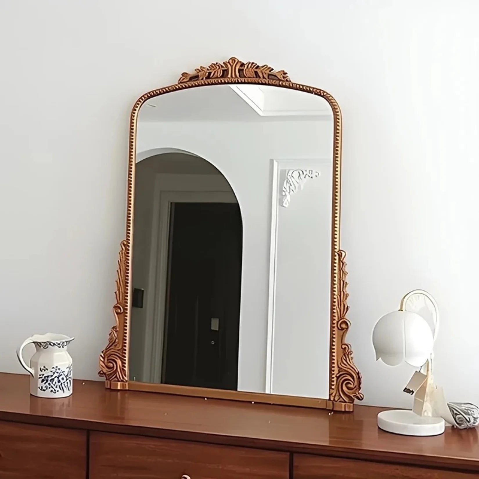 Miroir Louis Philippe doré posé sur commode en bois.