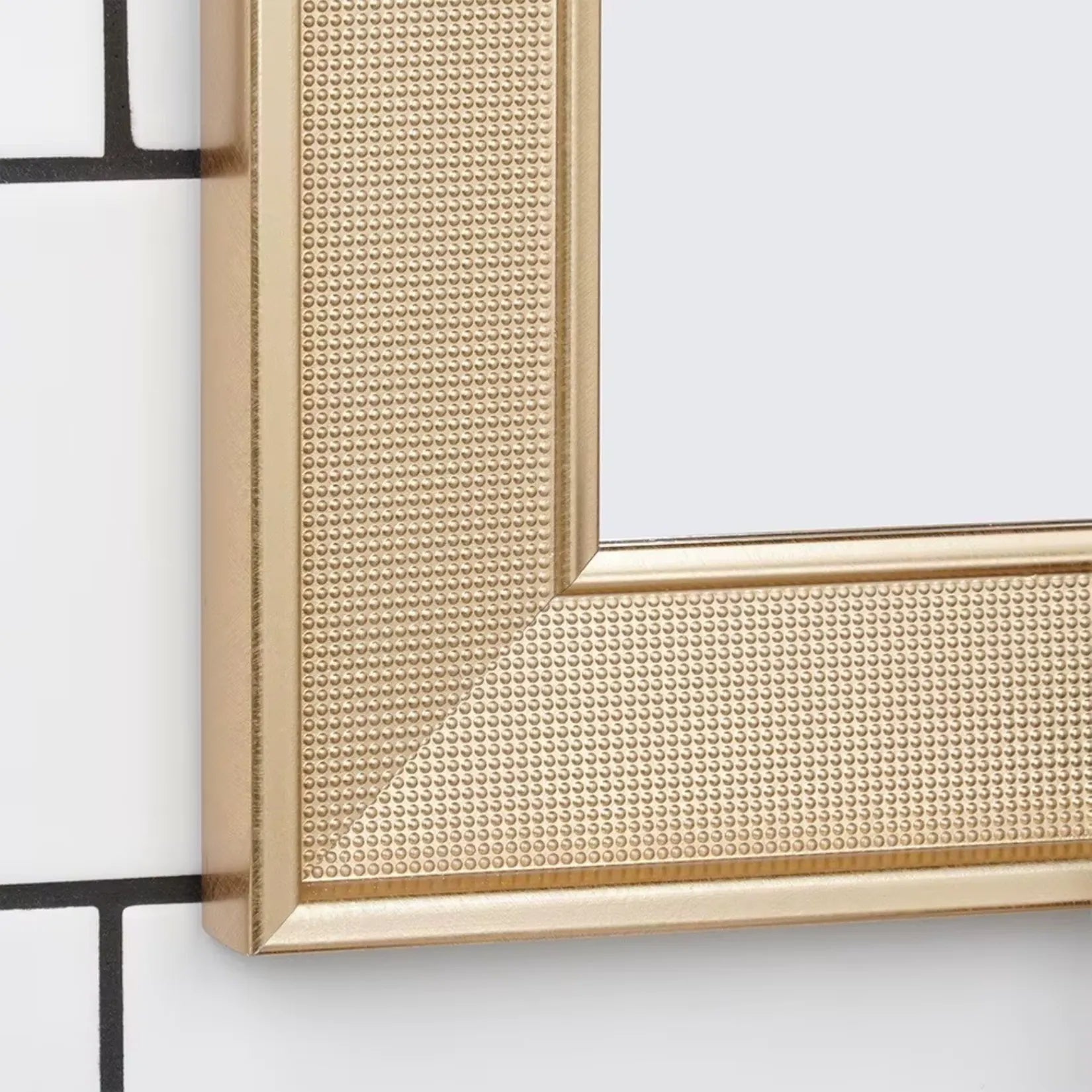 Zoom sur le cadre doré texturé du miroir mural rectangulaire.