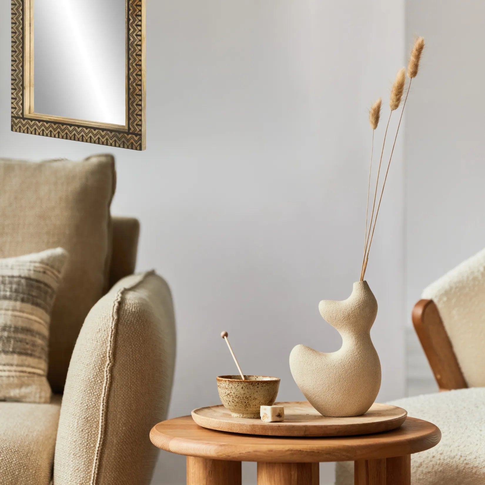 Miroir mural rectangulaire en bois de manguier au-dessus d’un meuble bas et décor organique.