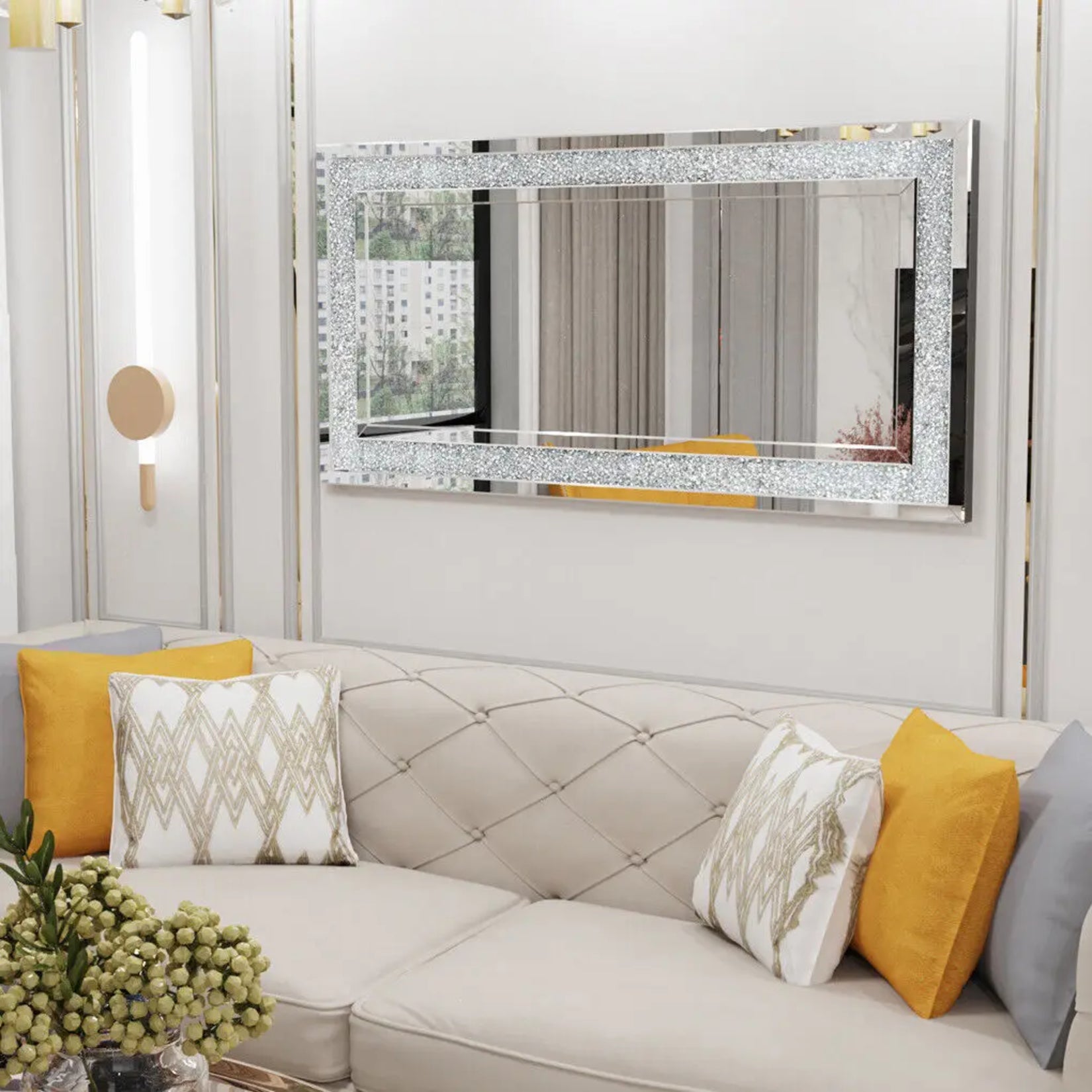 Miroir mural rectangulaire design avec cadre incrusté de cristaux placé au-dessus d’un canapé beige.