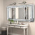 Miroir mural rectangulaire design avec cristaux incrustés installé au-dessus d’une coiffeuse blanche.