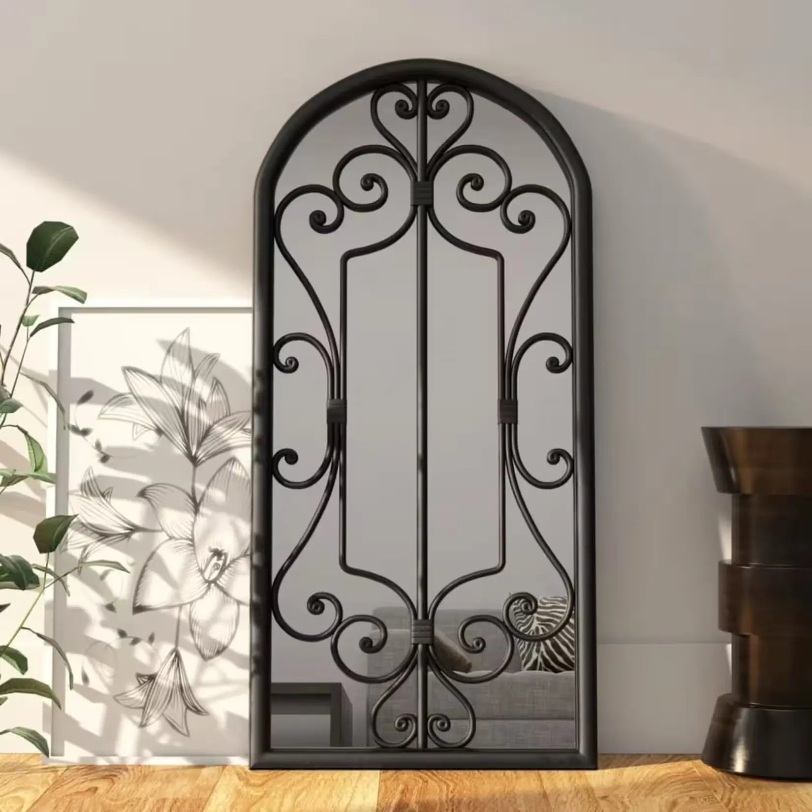 Miroir noir rectangulaire posé au sol dans un intérieur lumineux avec plantes.