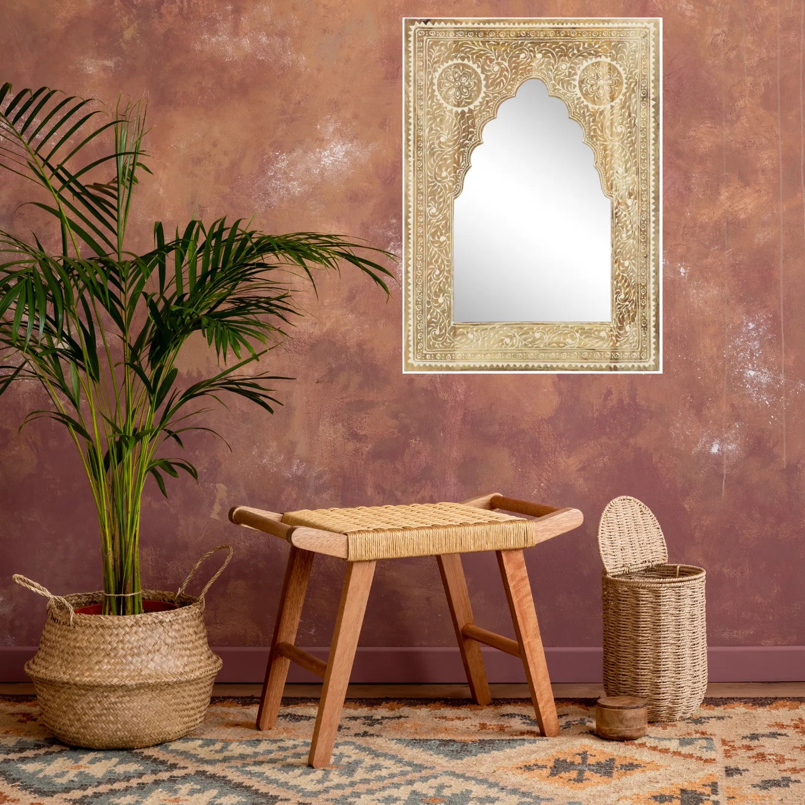 Miroir oriental suspendu sur un mur de teinte terre avec plante exotique.