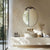 Miroir ovale doré accroché au mur au-dessus d'une commode en bois clair dans une chambre chaleureuse.