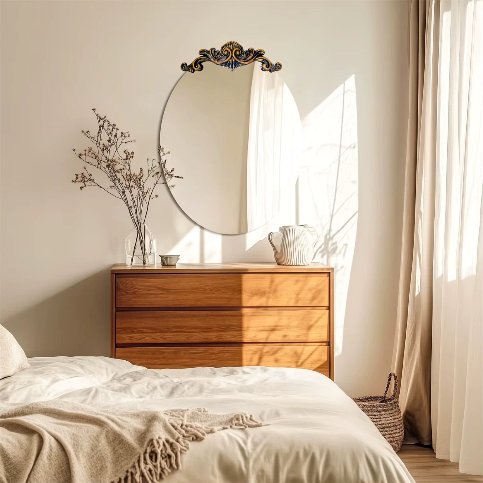 Miroir ovale doré accroché au mur au-dessus d'une commode en bois clair dans une chambre chaleureuse.