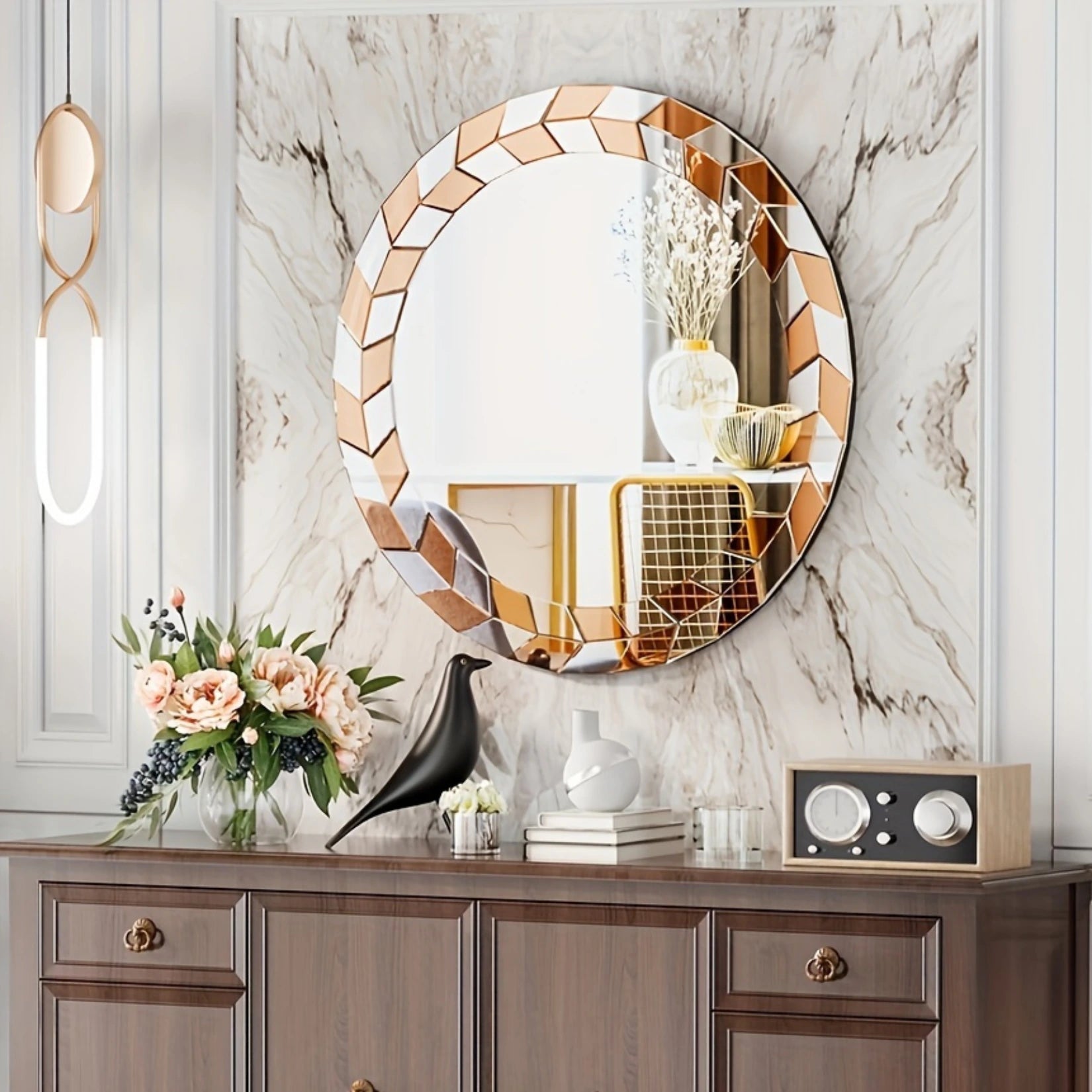 Miroir rond doré 60 cm posé sur mur marbré au-dessus d’un meuble bois foncé avec déco florale.