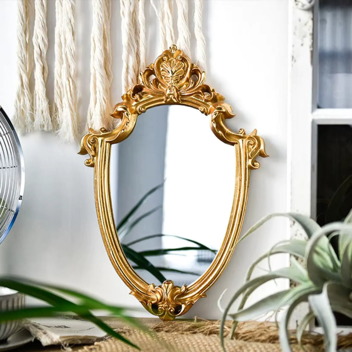 Miroir rond doré baroque posé au sol dans un design bohème.