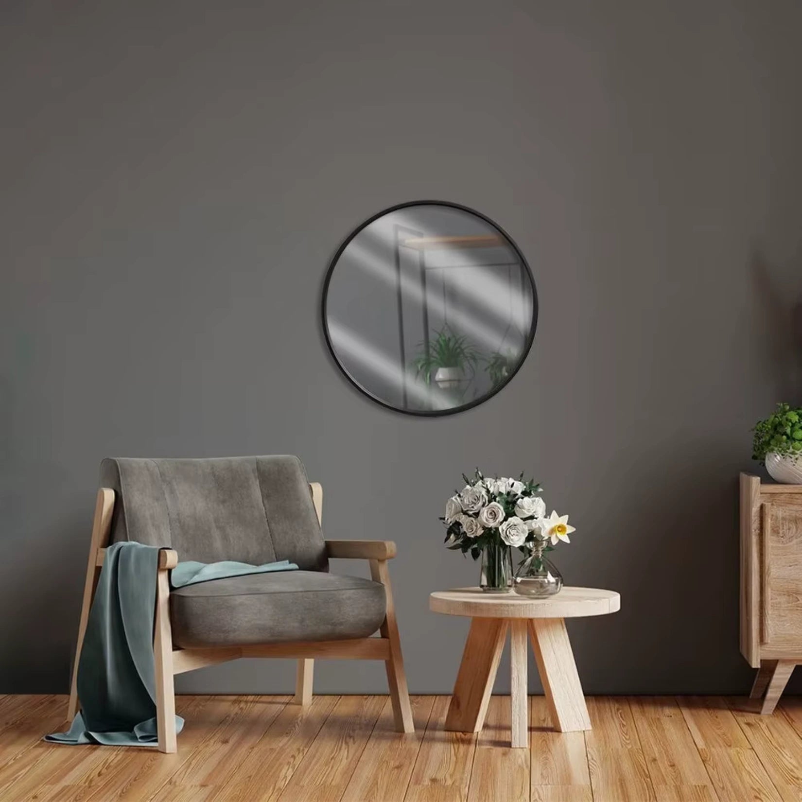 Miroir rond noir accroché sur un mur foncé, créant un effet de contraste élégant avec les meubles en bois clair.