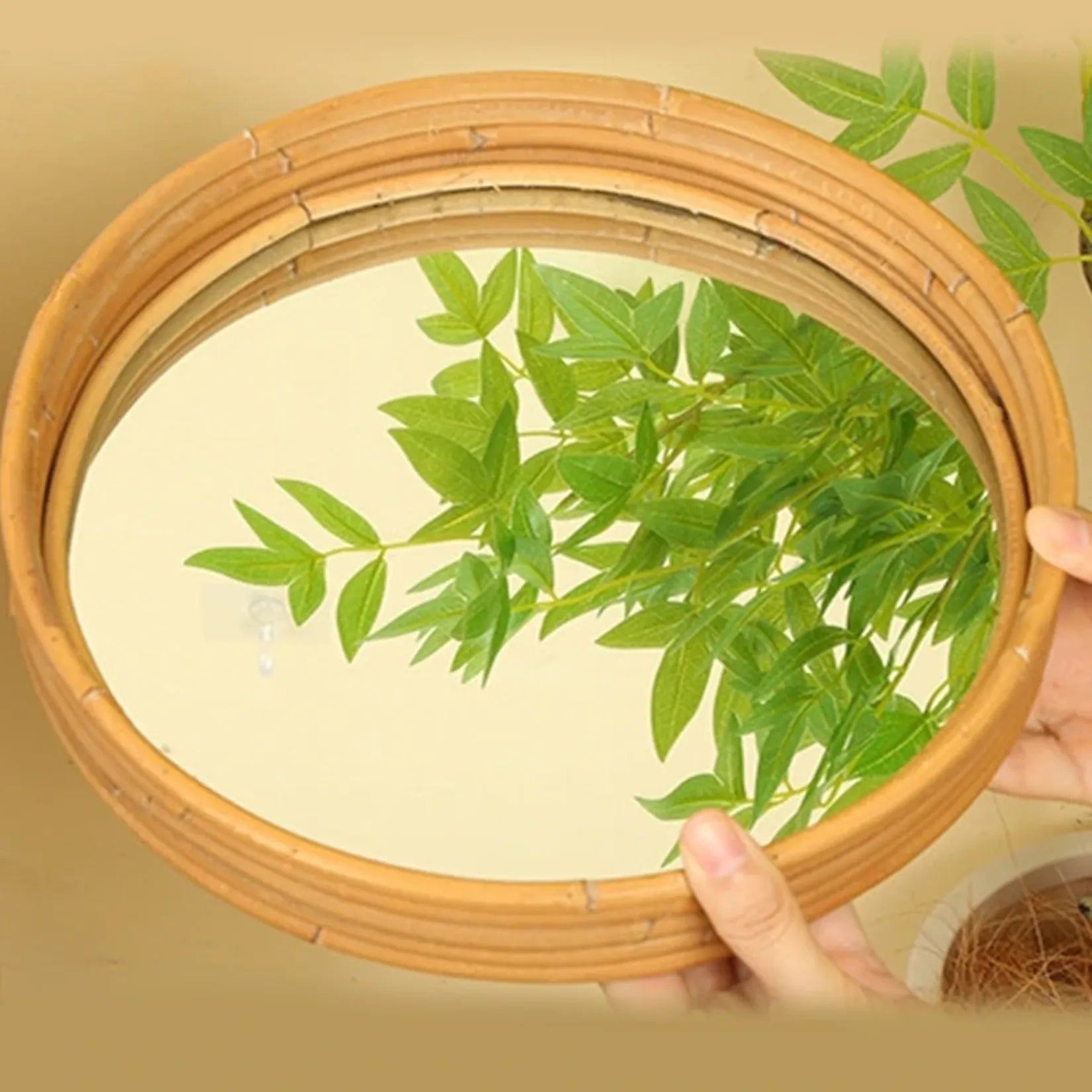 Miroir rond rotin reflétant un feuillage vert naturel.