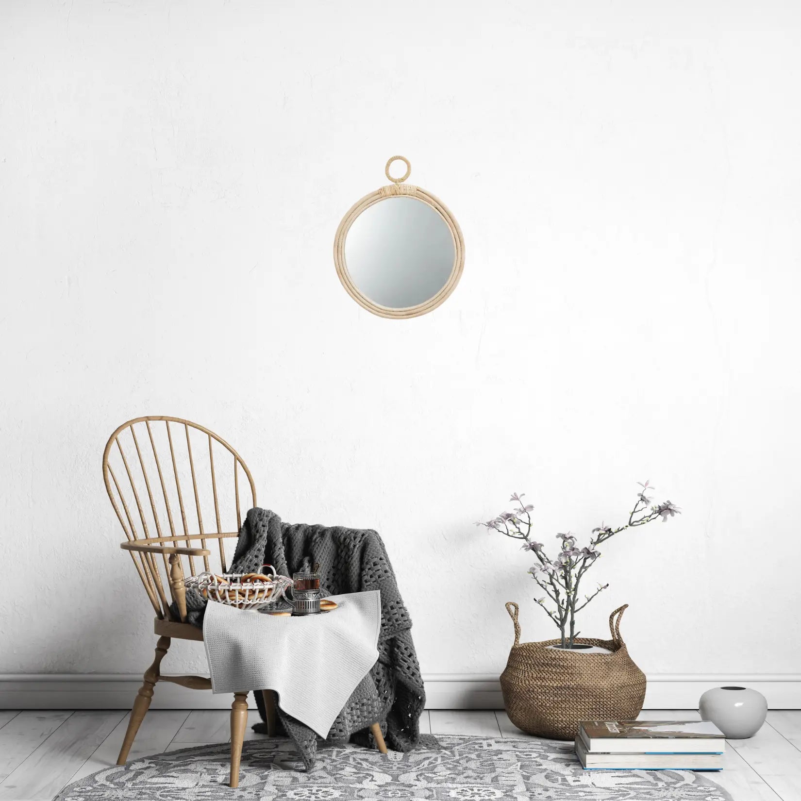 Miroir Rotin Rond avec anneau dans un intérieur scandinave épuré avec chaise en bois, plaid gris et panier en fibres naturelles.