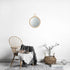 Miroir Rotin Rond avec anneau dans un intérieur scandinave épuré avec chaise en bois, plaid gris et panier en fibres naturelles.