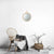 Miroir Rotin Rond avec anneau dans un intérieur scandinave épuré avec chaise en bois, plaid gris et panier en fibres naturelles.