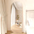 Miroir sur pied doré dans une chambre claire avec rideaux beiges.