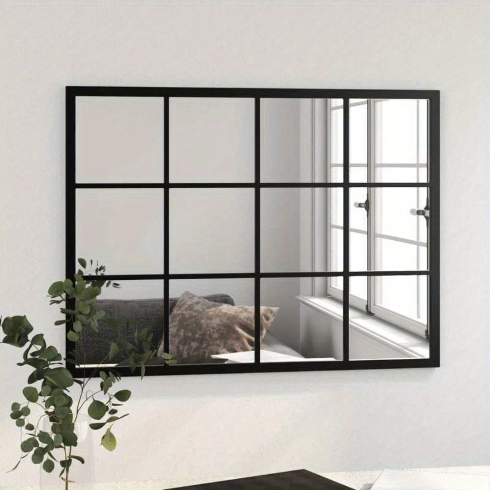 Miroir verrière industriel installé au mur, reflétant une fenêtre et un canapé cosy.