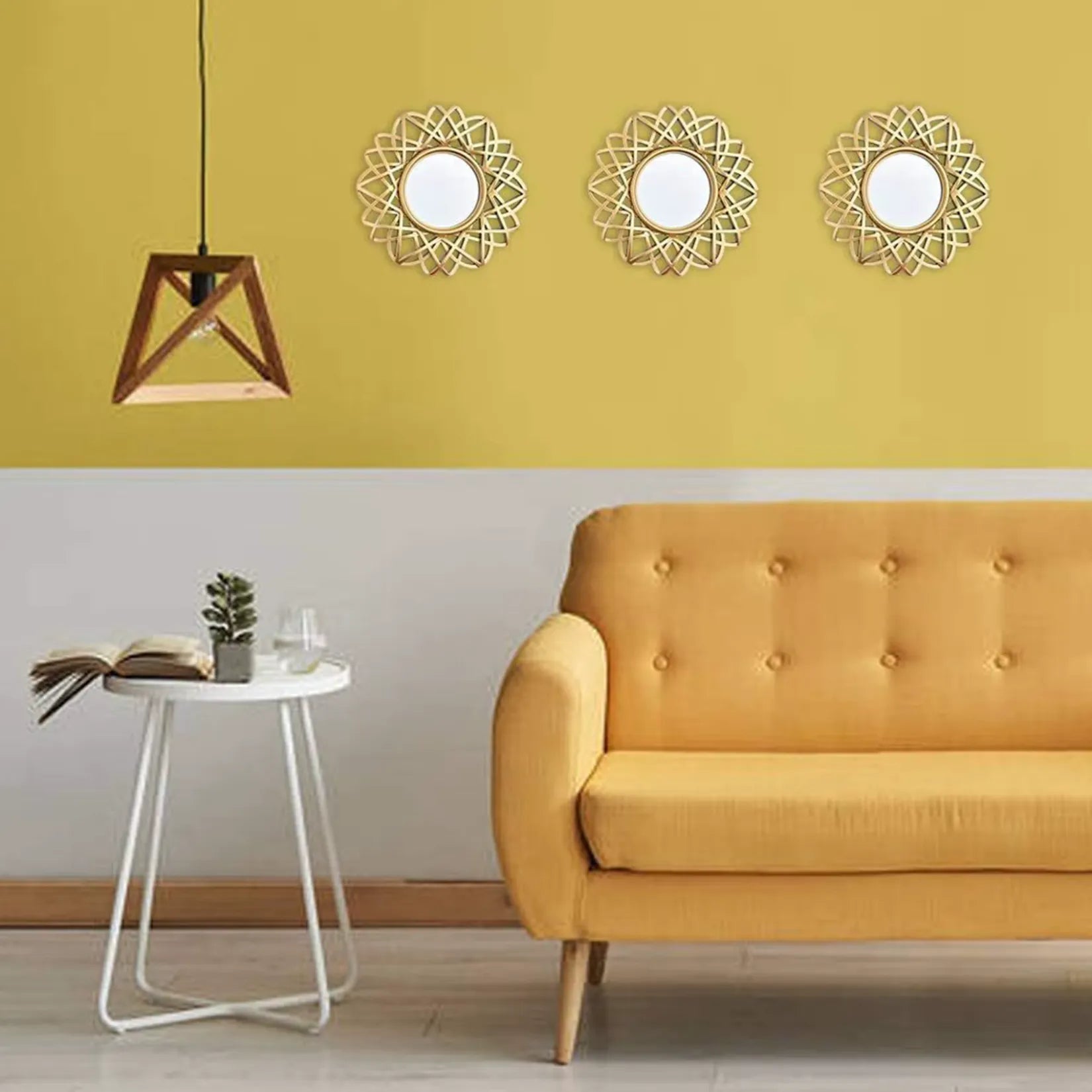 Miroir rond design doré accroché dans un salon scandinave aux murs roses avec fauteuil gris clair et lampe vintage.