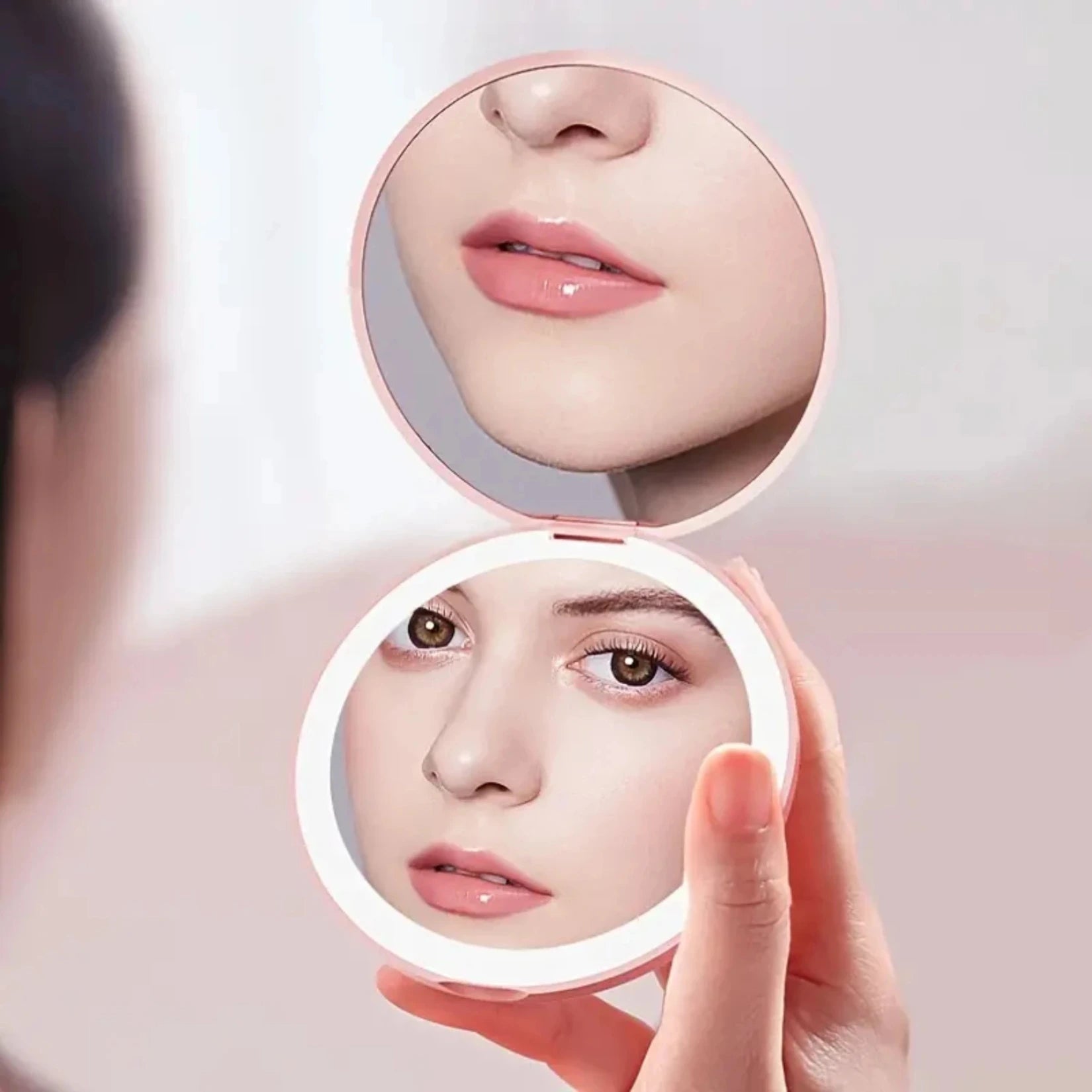 Petit miroir de poche avec double vue utilisé pour une retouche maquillage.