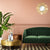 Petit miroir doré rond accroché sur un mur rose poudré dans un salon chic et coloré.