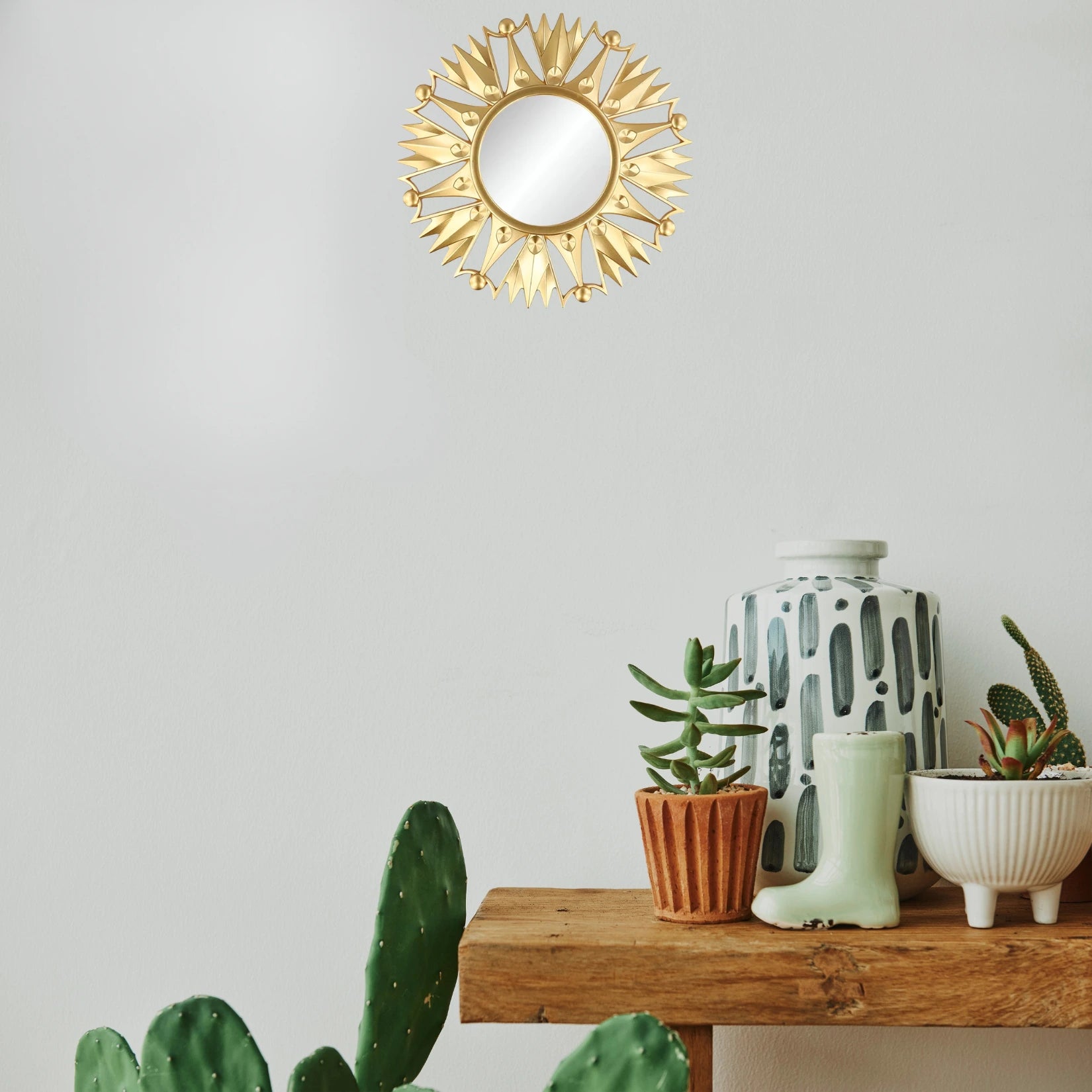 Petit miroir doré rond dans un intérieur bohème avec plantes vertes et décoration naturelle.