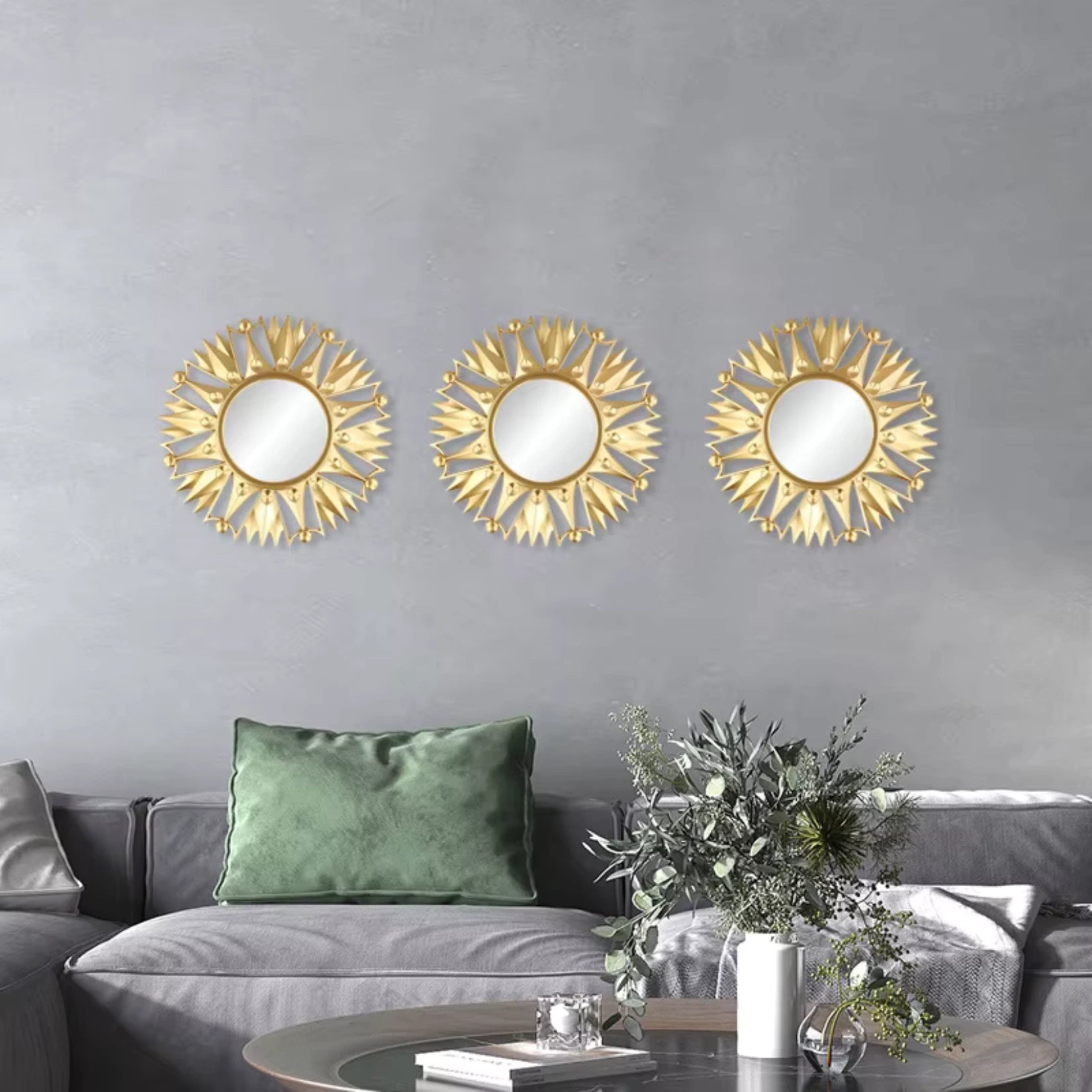 Trio de petits miroirs dorés ronds alignés sur un mur gris dans un salon contemporain.